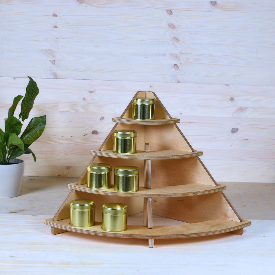 Light plywood corner stand with curved shelves displaying golden tins.