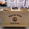 Light wooden portable cart with "Sips by Tom" branding and three round trays.