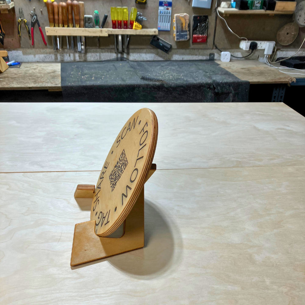 Wooden sign with QR code and text on a workshop counter