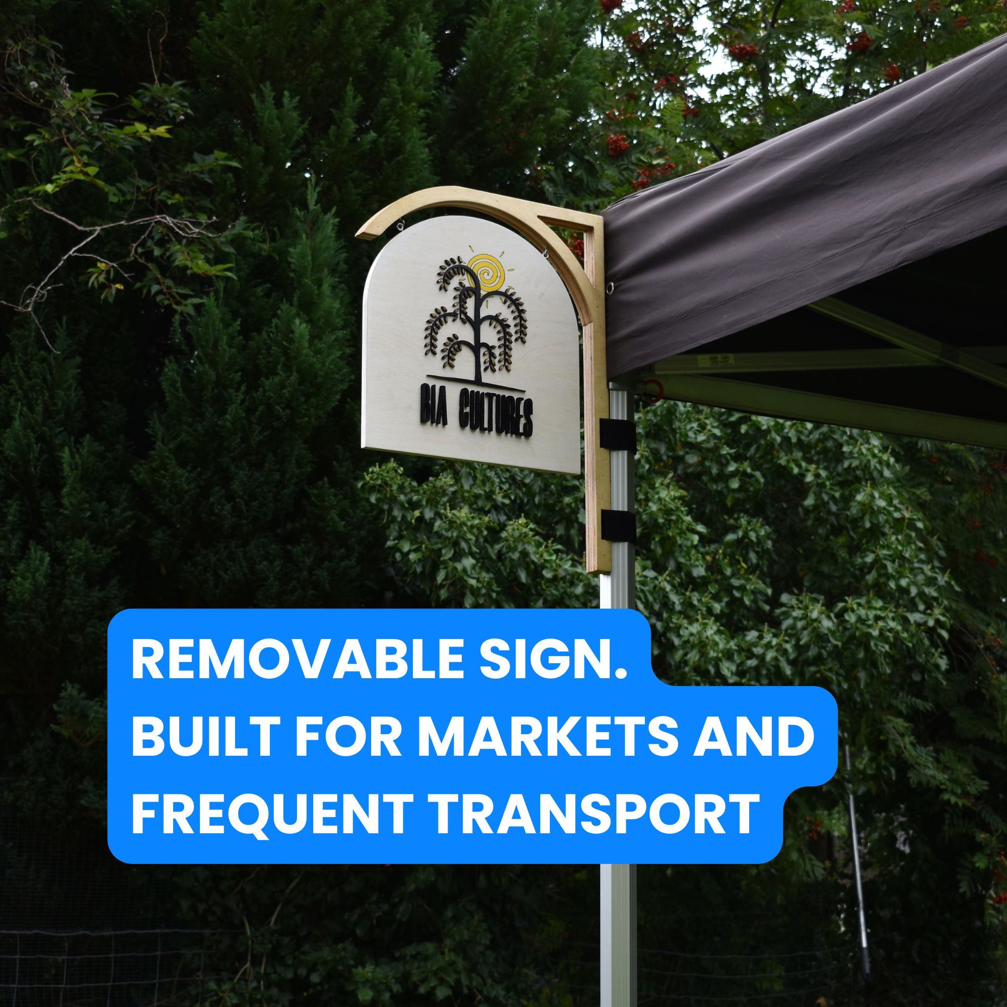 Removable sign on a market stand with text about markets and transport, against a green foliage background.