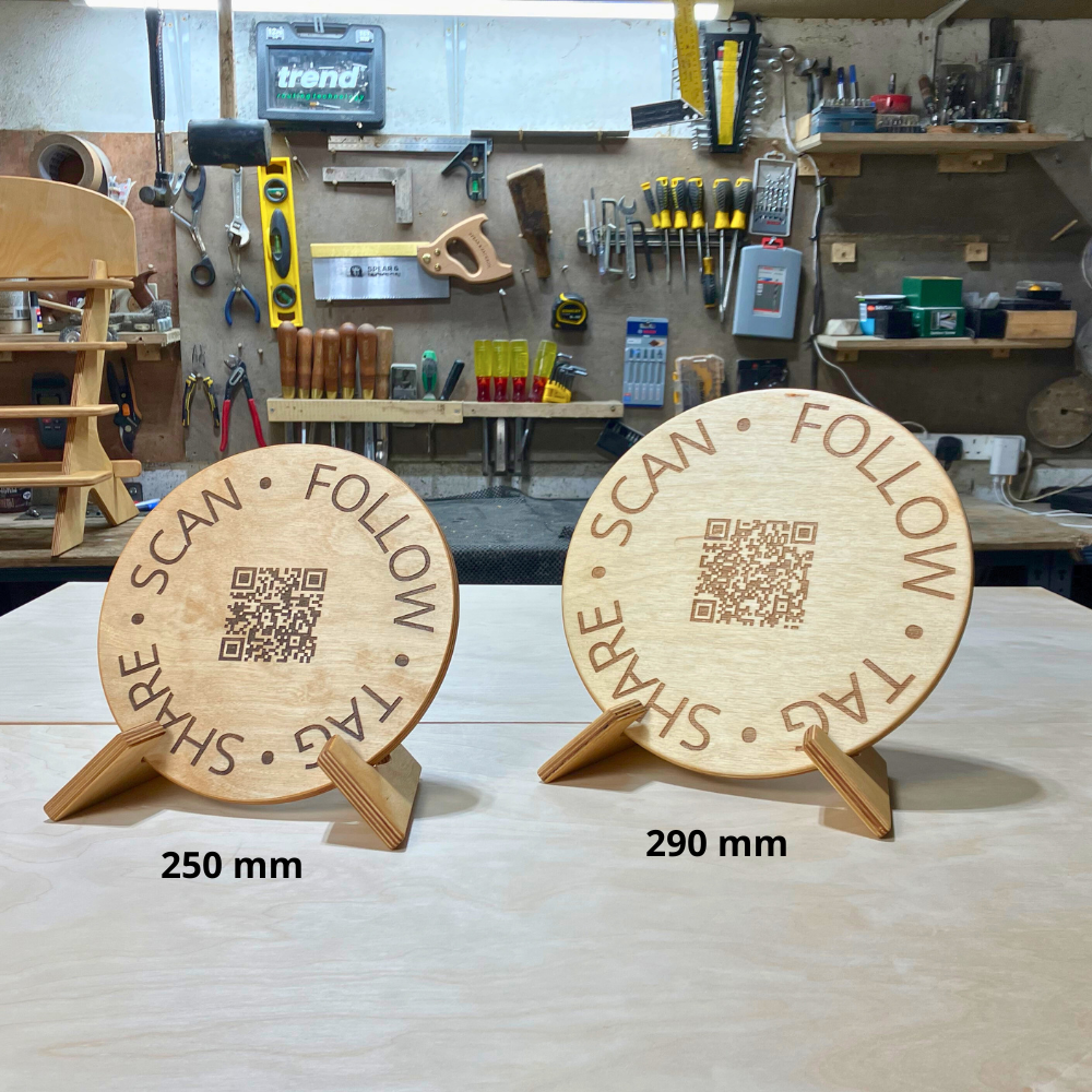 Two wooden circular signs with QR codes and text in a workshop setting.