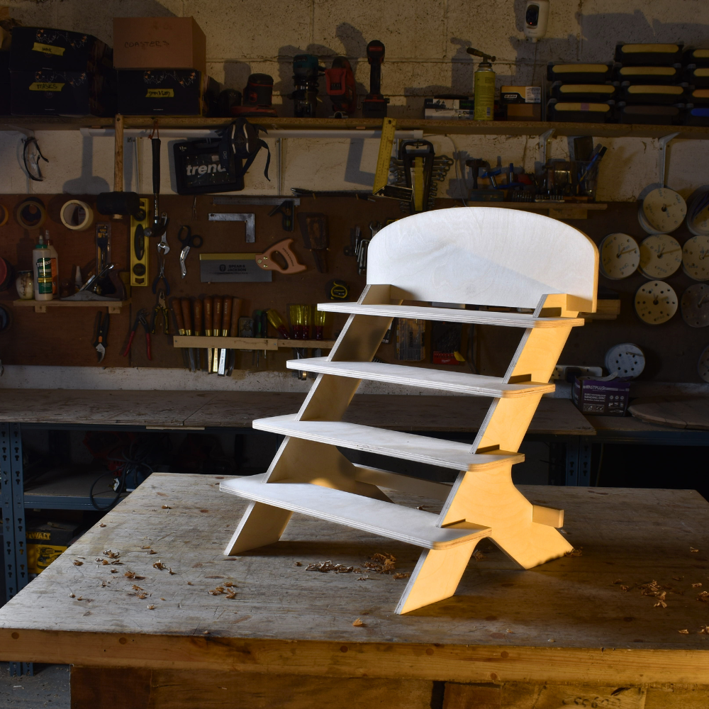 Wooden market stand on a workbench in a workshop with tools and equipment in the background.
